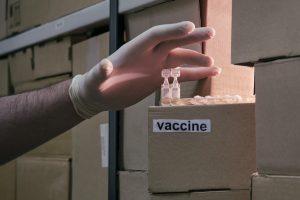 Lack of coronavirus vaccine in boxes in stock. A gloved hand steals medicines from a warehouse