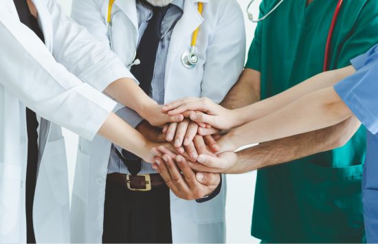 Group of happy doctor surgeon and nurse putting their hand together for teamwork in meeting on white background, Healthcare and medical concept